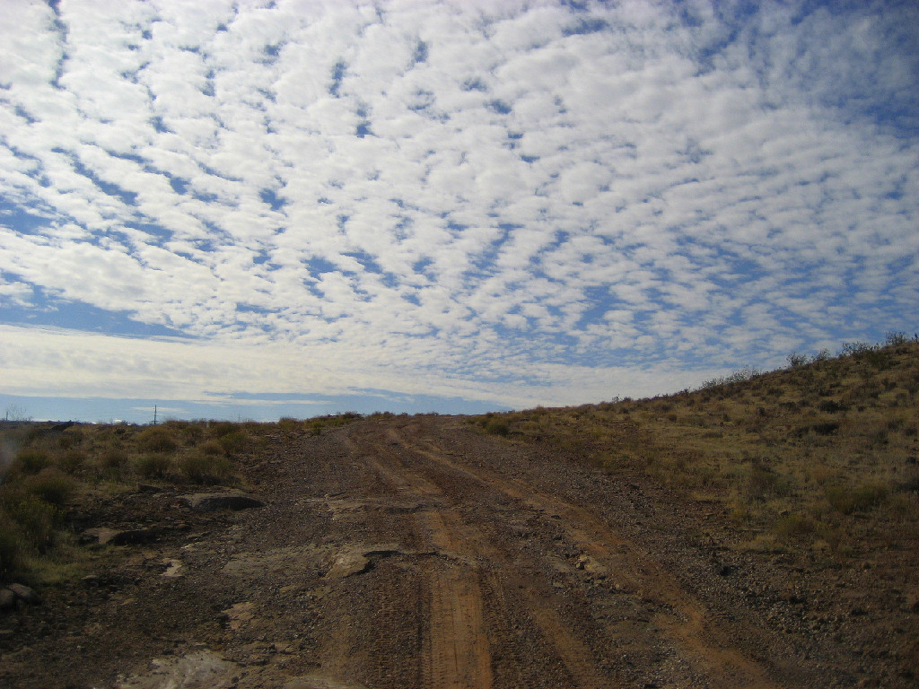 dirt road under cloud covered sky